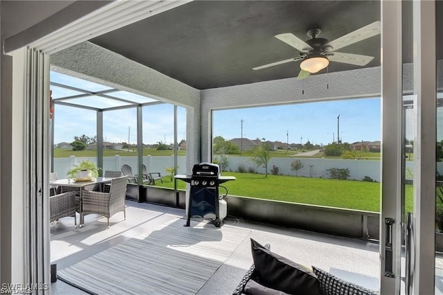 sunroom featuring a water view and ceiling fan