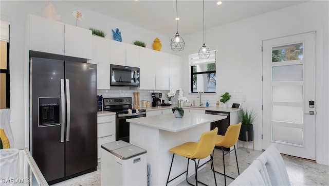 kitchen featuring white cabinets, backsplash, a kitchen island, black appliances, and pendant lighting