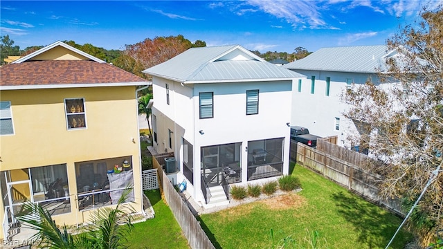 rear view of house featuring cooling unit, a yard, and a sunroom