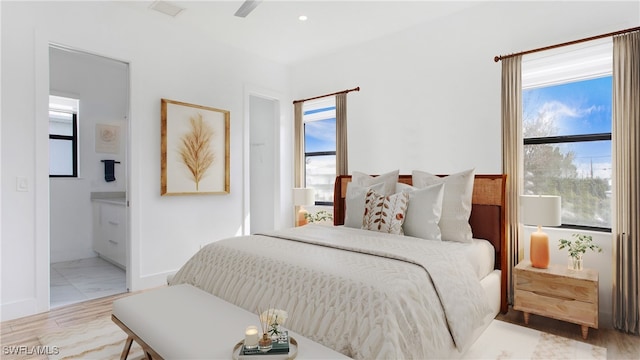 bedroom with light hardwood / wood-style floors, ensuite bathroom, and ceiling fan