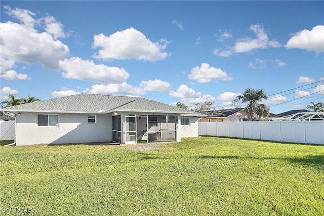 rear view of house featuring a sunroom and a yard