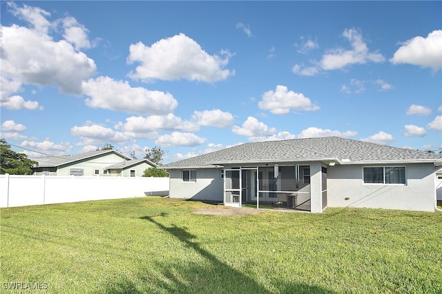 rear view of property featuring a sunroom and a lawn