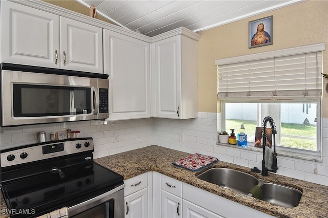 kitchen featuring sink, dark stone countertops, appliances with stainless steel finishes, tasteful backsplash, and white cabinetry