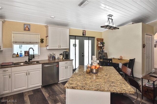 kitchen featuring stainless steel dishwasher, white cabinets, sink, and hanging light fixtures