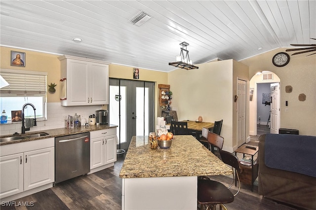 kitchen with dark hardwood / wood-style flooring, stainless steel dishwasher, sink, white cabinets, and hanging light fixtures