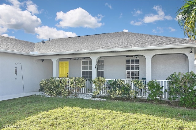 view of exterior entry with a yard and a porch