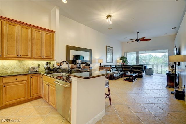 kitchen featuring a kitchen bar, dishwasher, kitchen peninsula, and dark stone counters