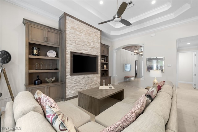 living room with ornamental molding, built in features, ceiling fan, and a tray ceiling