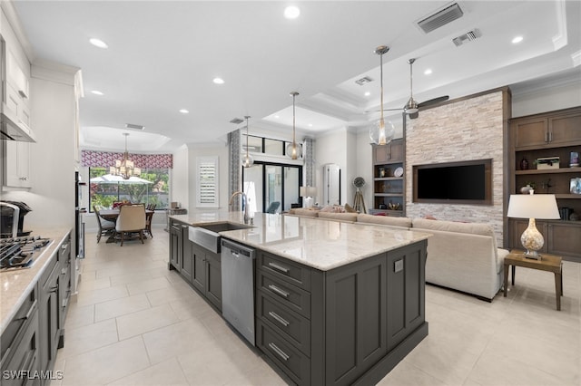 kitchen featuring sink, appliances with stainless steel finishes, a spacious island, a tray ceiling, and decorative light fixtures