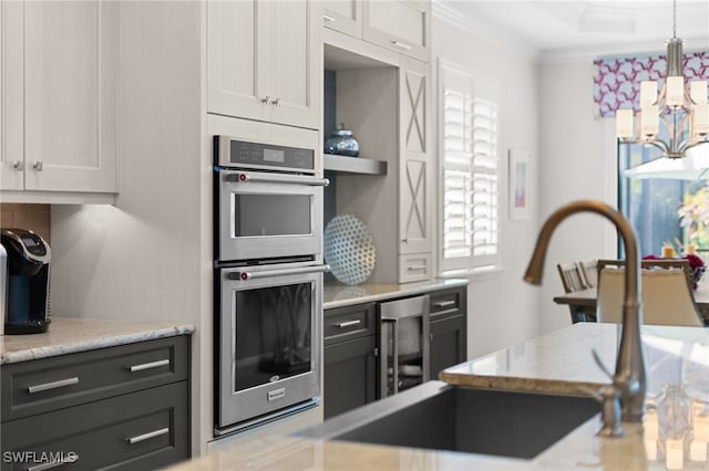 kitchen with white cabinetry, crown molding, double oven, and pendant lighting