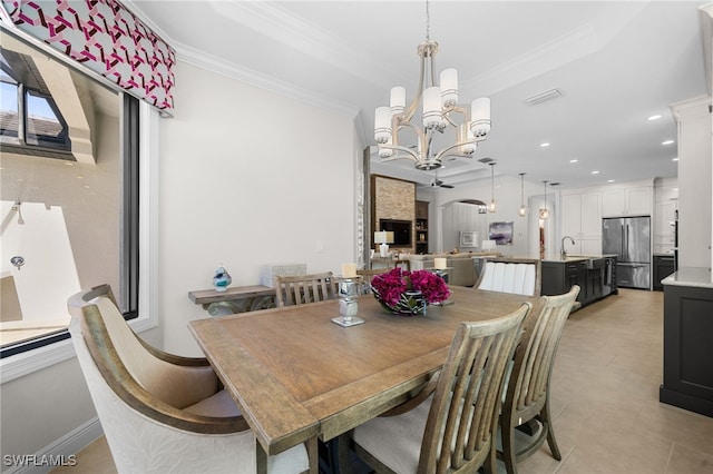 dining area with sink, a chandelier, ornamental molding, light tile patterned floors, and a raised ceiling