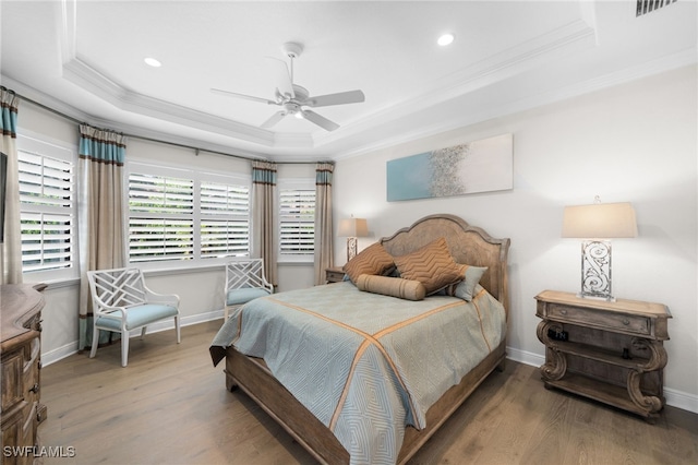 bedroom featuring wood-type flooring, ornamental molding, a raised ceiling, and ceiling fan