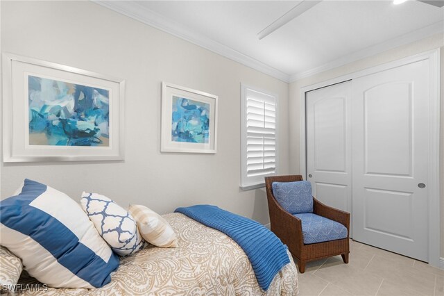 bedroom with light tile patterned floors, crown molding, and a closet