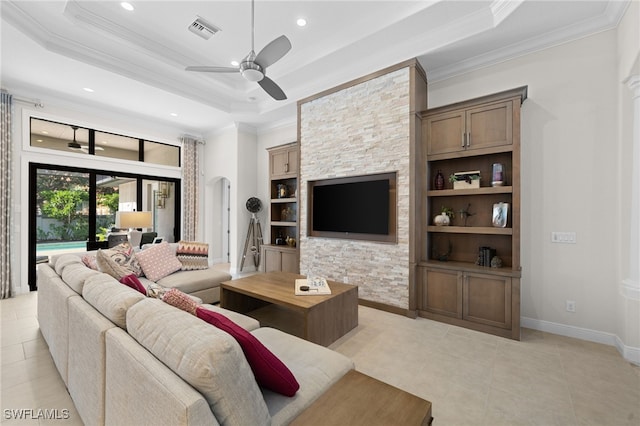 living room with a raised ceiling, ornamental molding, built in features, and ceiling fan