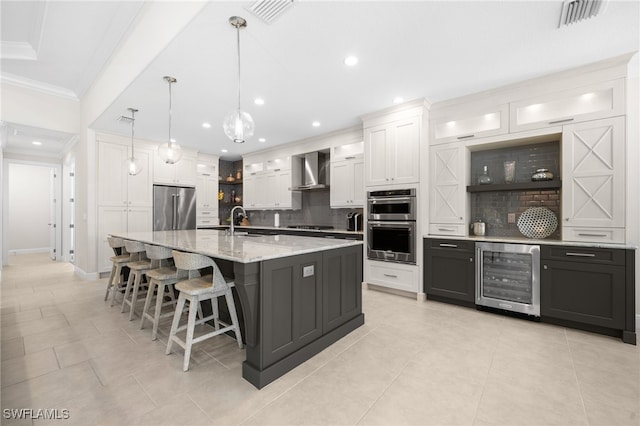 kitchen featuring sink, white cabinets, wine cooler, stainless steel appliances, and wall chimney exhaust hood