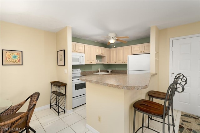 kitchen with white appliances, a kitchen breakfast bar, ceiling fan, light tile patterned floors, and kitchen peninsula