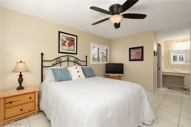 tiled bedroom with a textured ceiling, ensuite bathroom, and ceiling fan