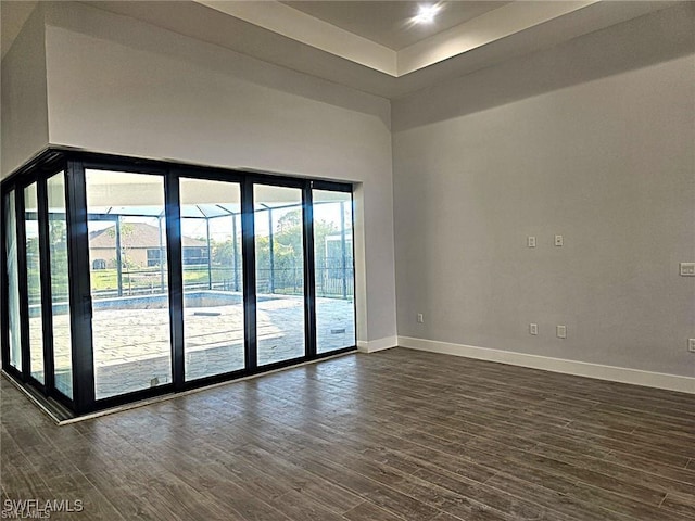 spare room featuring a towering ceiling, dark wood-type flooring, and a raised ceiling