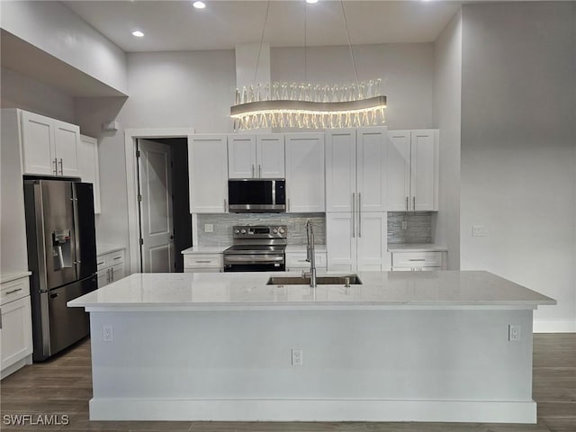 kitchen featuring a kitchen island with sink, sink, light stone countertops, and appliances with stainless steel finishes