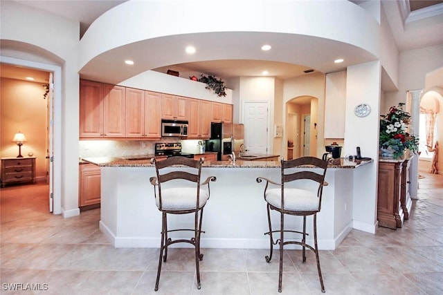 8921 Crown Colony Blvd, Fort Myers, FL 33908 - kitchen featuring stainless steel appliances, arched walkways, stone counters, a kitchen bar, and recessed lighting