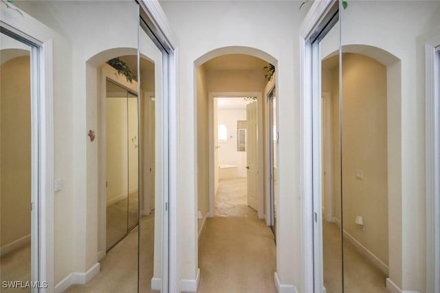 8921 Crown Colony Blvd, Fort Myers, FL 33908 - hallway featuring arched walkways, light colored carpet, and baseboards