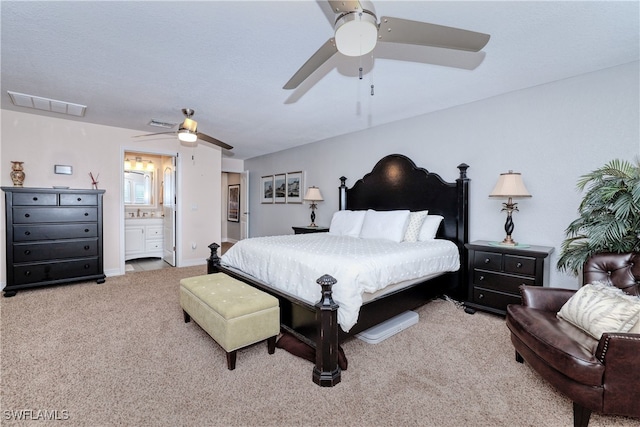 carpeted bedroom with ensuite bathroom and ceiling fan