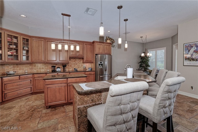 kitchen with stainless steel fridge with ice dispenser, a breakfast bar area, and a kitchen island with sink