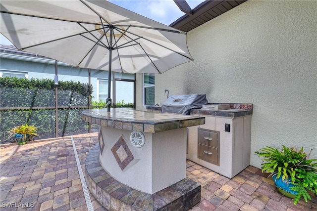 view of patio featuring exterior kitchen, a bar, and a grill