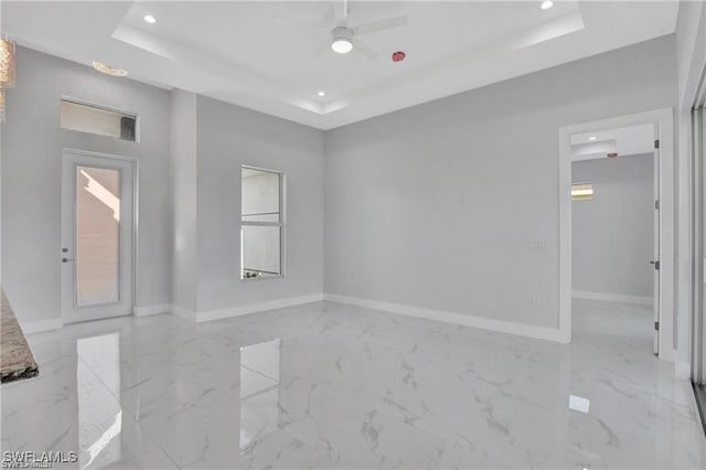 empty room with a raised ceiling and ceiling fan