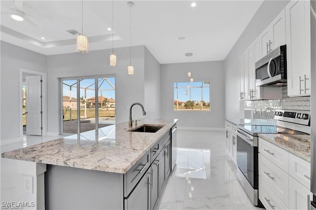 kitchen featuring stainless steel appliances, white cabinetry, hanging light fixtures, and sink