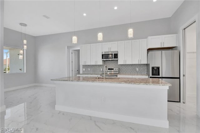 kitchen with decorative light fixtures, white cabinetry, stainless steel appliances, and a kitchen island with sink