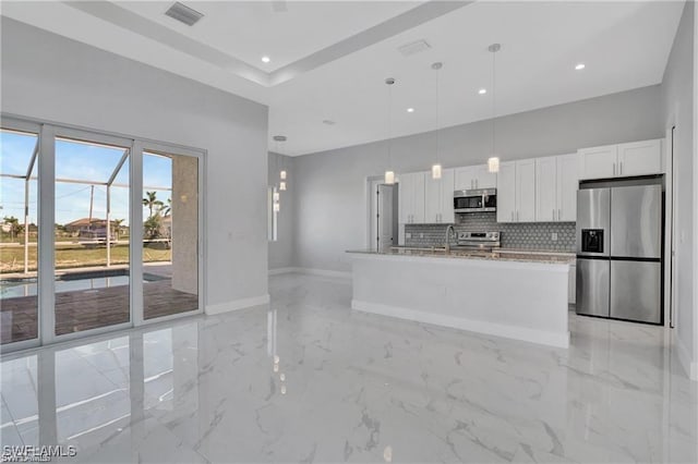 kitchen featuring a kitchen island with sink, white cabinets, hanging light fixtures, tasteful backsplash, and stainless steel appliances