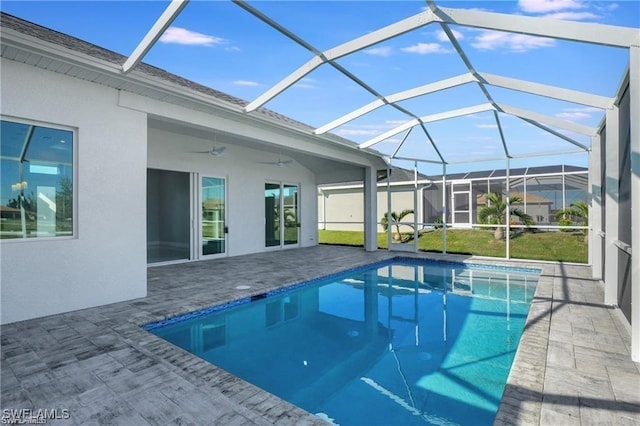 view of pool with a patio, glass enclosure, and ceiling fan