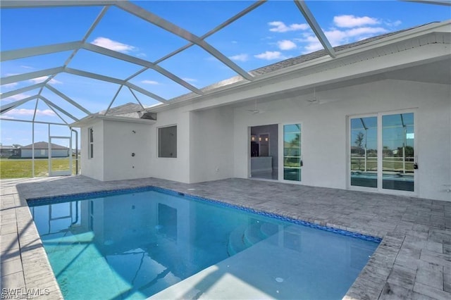 view of swimming pool with glass enclosure, ceiling fan, and a patio