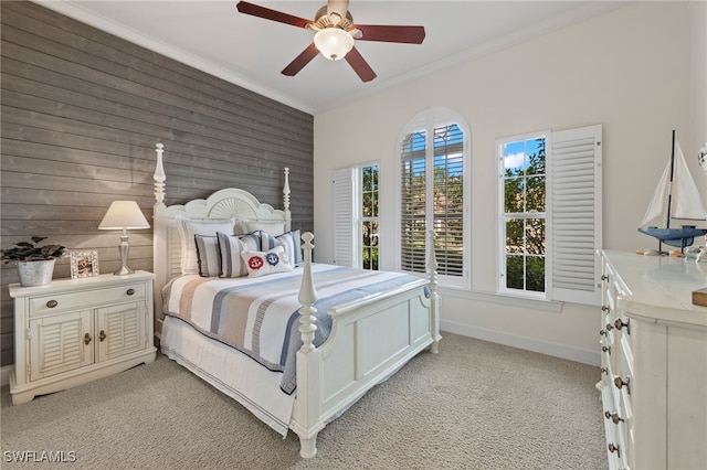 carpeted bedroom featuring ceiling fan, wood walls, and ornamental molding