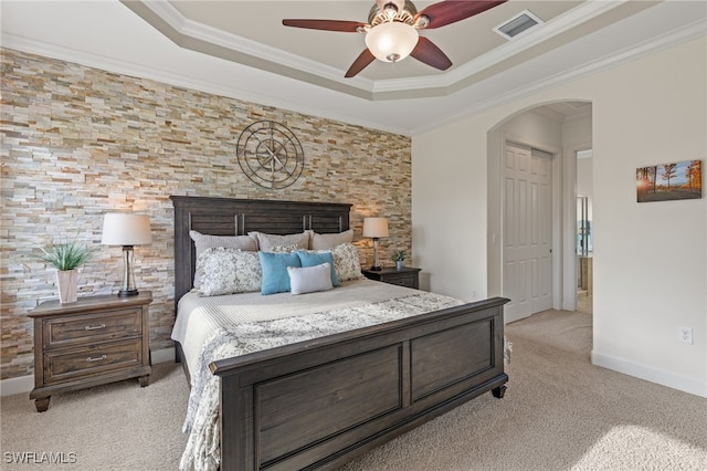 carpeted bedroom featuring a tray ceiling, ceiling fan, and ornamental molding