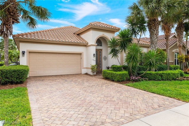 mediterranean / spanish-style home with decorative driveway, an attached garage, and stucco siding