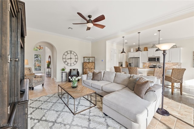 living area featuring arched walkways, crown molding, stone tile floors, visible vents, and ceiling fan