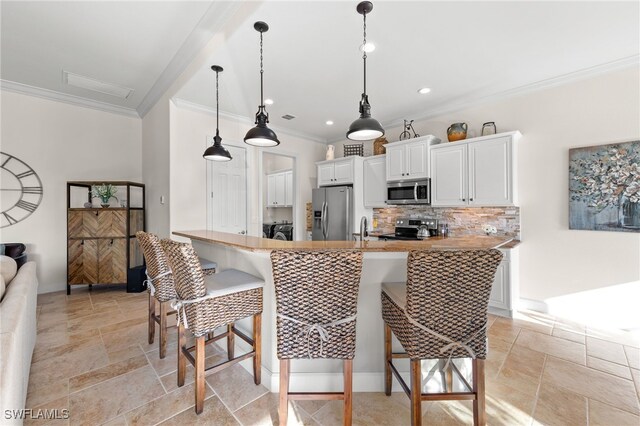 kitchen featuring white cabinets, a kitchen breakfast bar, sink, appliances with stainless steel finishes, and kitchen peninsula