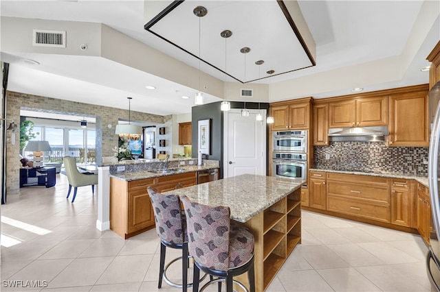 kitchen featuring a center island, hanging light fixtures, sink, a kitchen breakfast bar, and appliances with stainless steel finishes