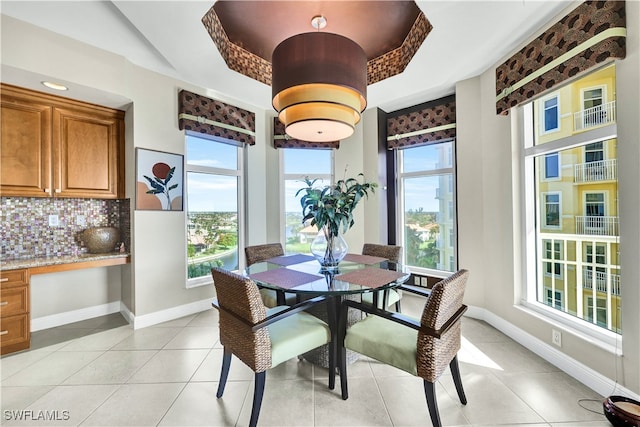 dining space with plenty of natural light, light tile patterned floors, and a tray ceiling