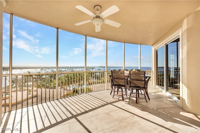 sunroom / solarium with a water view and ceiling fan