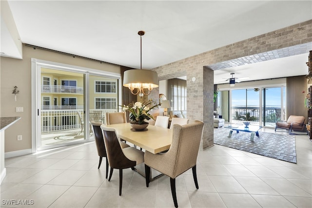 dining room with light tile patterned flooring, ceiling fan with notable chandelier, and brick wall