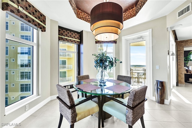 dining area with light tile patterned floors and a tray ceiling