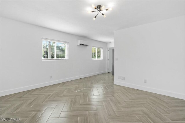 unfurnished room featuring light parquet flooring, a wall unit AC, and an inviting chandelier