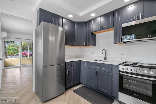 kitchen with light parquet floors, appliances with stainless steel finishes, gray cabinets, and sink