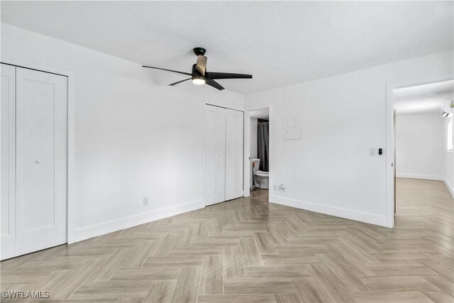 unfurnished bedroom featuring ceiling fan, light parquet flooring, and ensuite bath