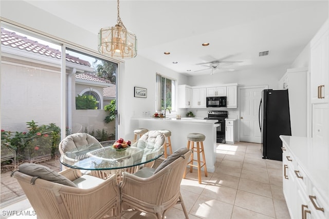 tiled dining area featuring sink and ceiling fan with notable chandelier