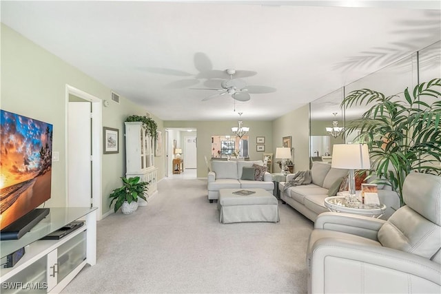 living area with ceiling fan with notable chandelier and carpet