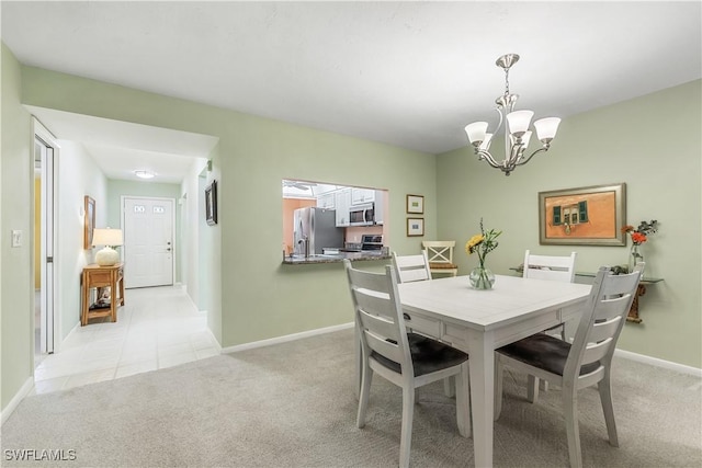 dining room featuring light carpet, a notable chandelier, and baseboards